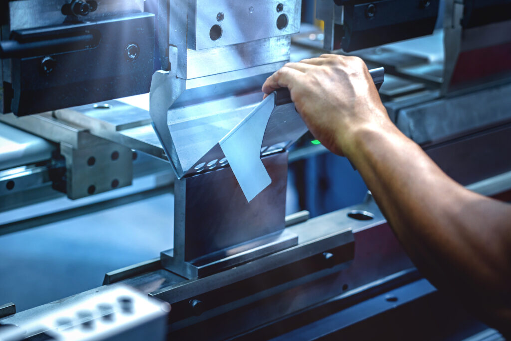 Workers bending sheet metal by CNC machines in industrial plants
